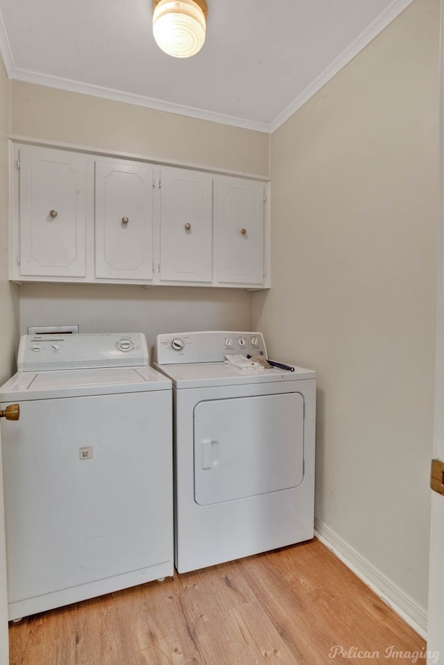 washroom featuring light hardwood / wood-style floors, crown molding, washing machine and dryer, and cabinets