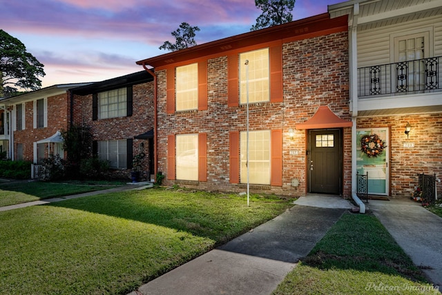 townhome / multi-family property featuring a balcony and a yard