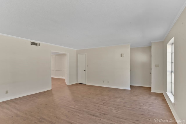 spare room with ornamental molding, plenty of natural light, and light hardwood / wood-style floors