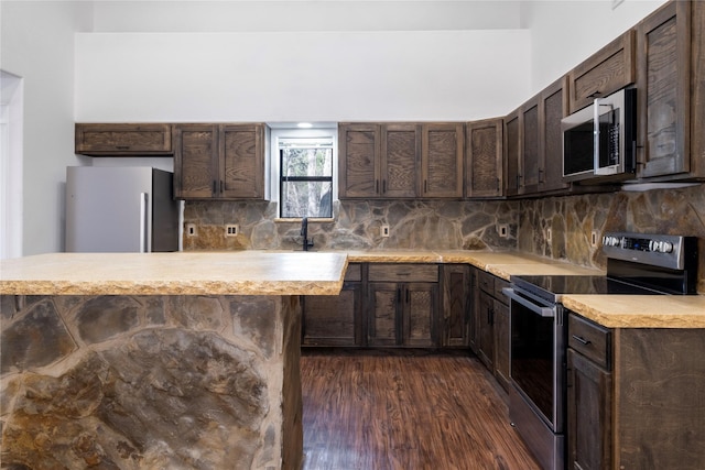 kitchen with backsplash, dark brown cabinets, stainless steel appliances, and dark hardwood / wood-style floors