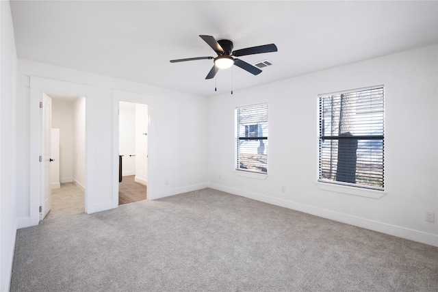 unfurnished bedroom featuring light carpet, ceiling fan, and ensuite bath