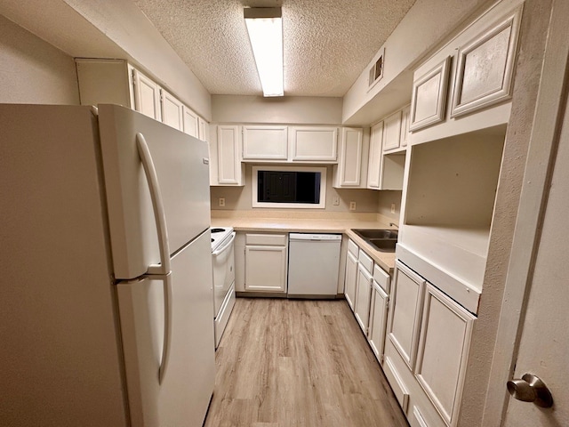 kitchen with white cabinetry, white appliances, a textured ceiling, light hardwood / wood-style flooring, and sink