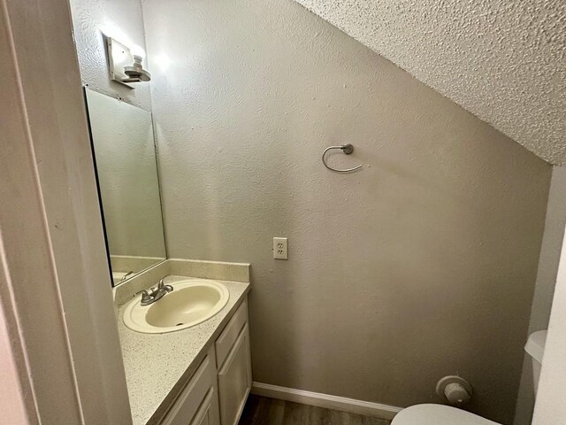 bathroom with vanity, toilet, wood finished floors, and baseboards