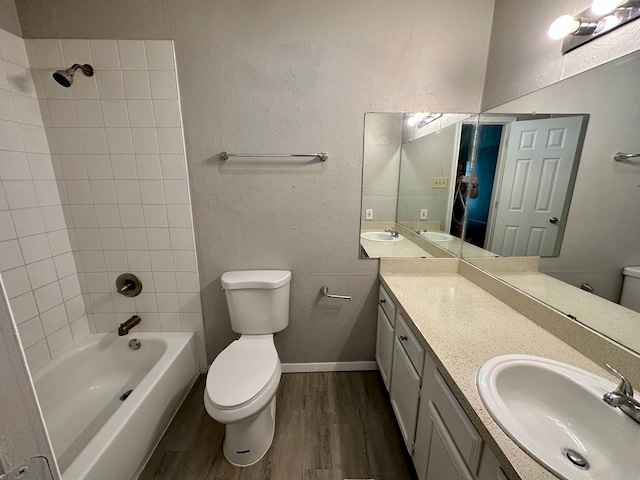 full bathroom featuring vanity, tiled shower / bath, hardwood / wood-style floors, and toilet