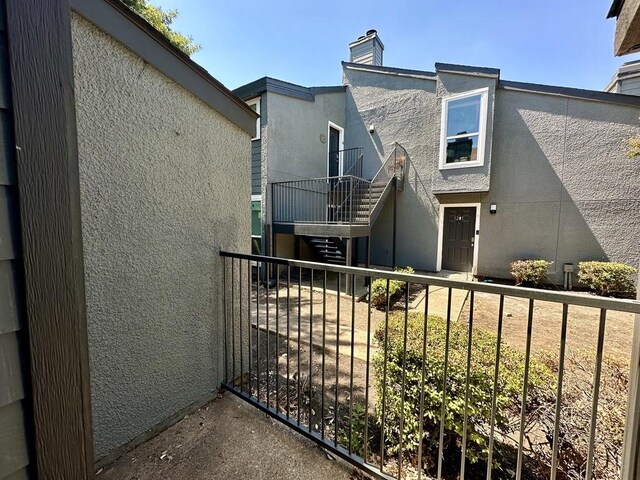 view of front of home featuring stairway, a chimney, and stucco siding
