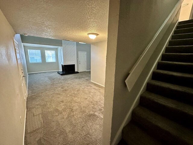 staircase with baseboards, a textured ceiling, and carpet flooring