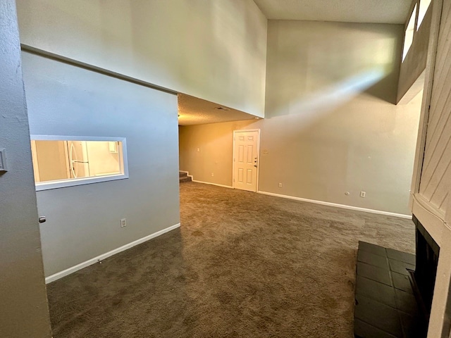 interior space with a towering ceiling, dark colored carpet, and a textured ceiling