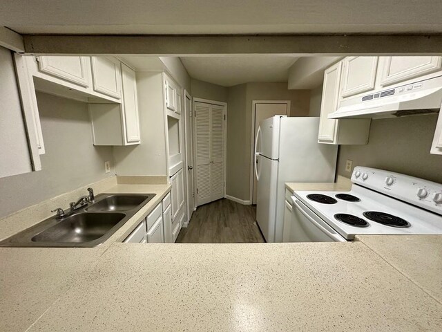 kitchen featuring under cabinet range hood, white appliances, light countertops, and a sink