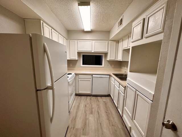 kitchen featuring a textured ceiling, white appliances, light wood-style floors, white cabinets, and light countertops