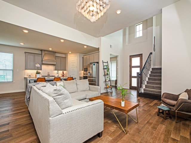 living room with a high ceiling, plenty of natural light, dark hardwood / wood-style floors, and a chandelier