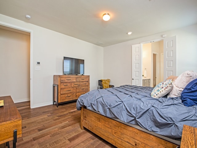 bedroom featuring ensuite bath and dark hardwood / wood-style flooring