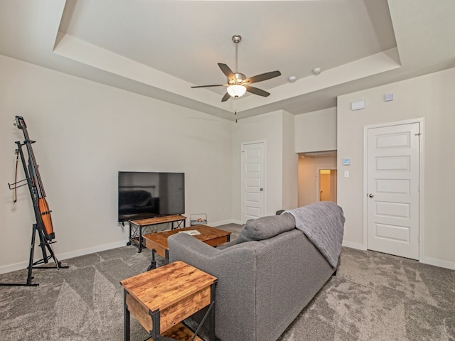 carpeted living room with a tray ceiling and ceiling fan