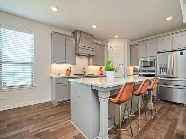 kitchen with a kitchen island with sink, dark hardwood / wood-style floors, stainless steel appliances, and plenty of natural light