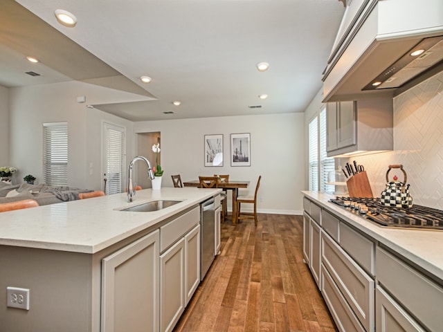 kitchen with hardwood / wood-style floors, a kitchen island with sink, sink, and gray cabinets