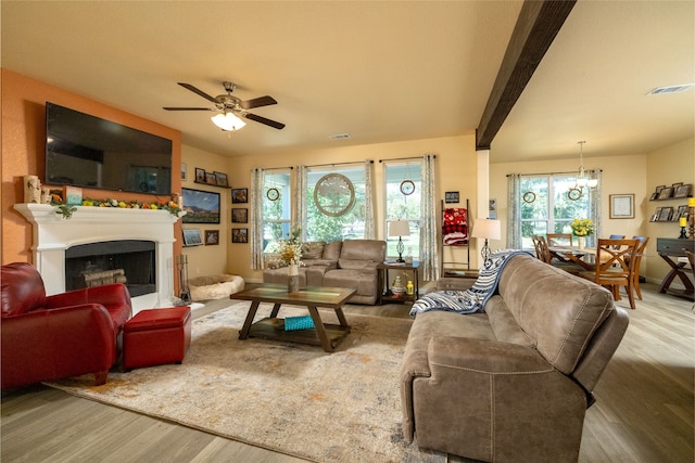 living room featuring ceiling fan with notable chandelier, hardwood / wood-style floors, and beamed ceiling