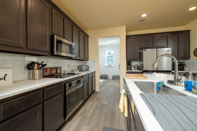 kitchen featuring dark brown cabinetry, sink, light hardwood / wood-style flooring, appliances with stainless steel finishes, and decorative backsplash