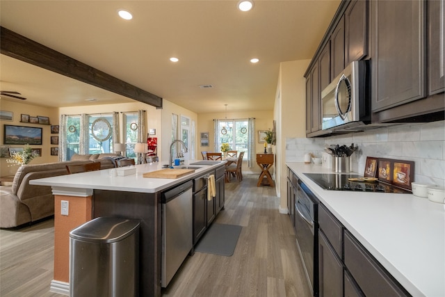 kitchen featuring dark brown cabinets, a center island with sink, stainless steel appliances, and light hardwood / wood-style flooring