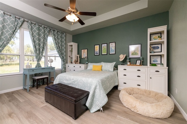 bedroom featuring a tray ceiling, ceiling fan, and light hardwood / wood-style flooring