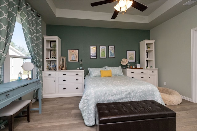 bedroom featuring a raised ceiling, ceiling fan, and hardwood / wood-style flooring