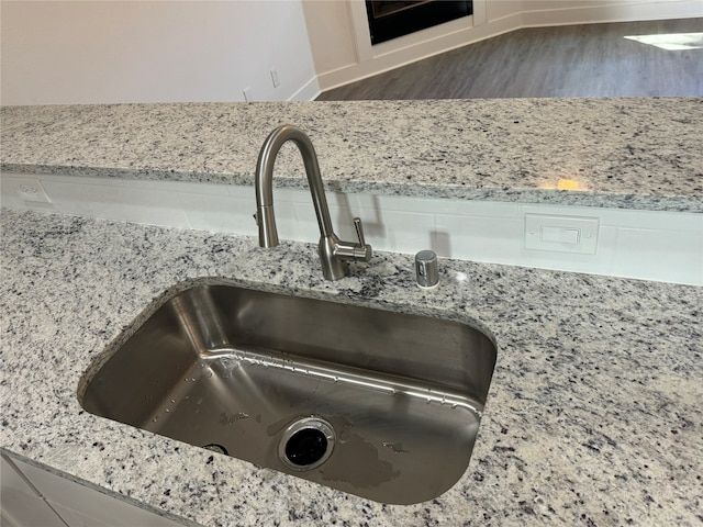 interior details featuring light stone countertops, dark hardwood / wood-style floors, and sink