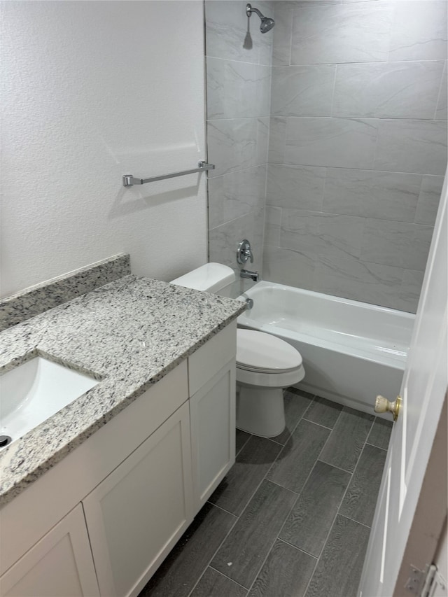 full bathroom featuring tiled shower / bath combo, vanity, and toilet