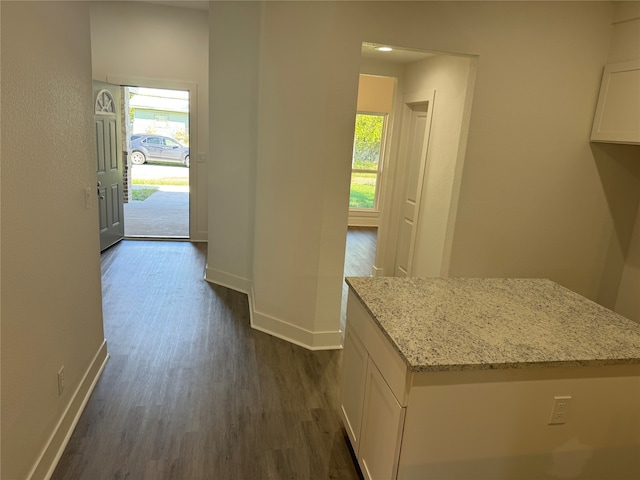 kitchen with light stone countertops, white cabinetry, and dark hardwood / wood-style flooring