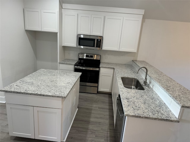 kitchen with appliances with stainless steel finishes, white cabinetry, light stone counters, dark hardwood / wood-style floors, and sink