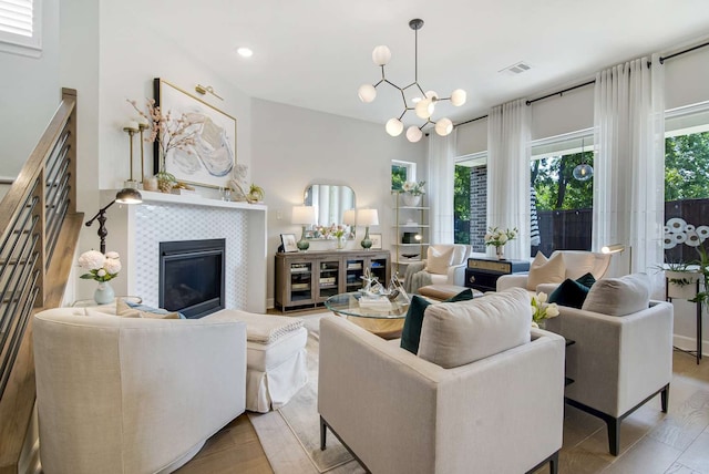 living room with a tiled fireplace, light hardwood / wood-style flooring, and a notable chandelier