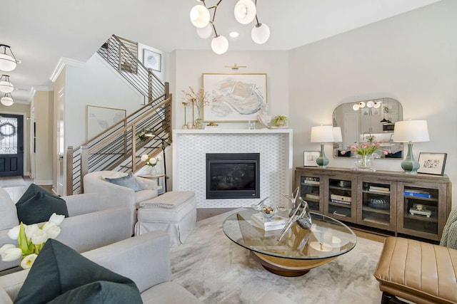 living room featuring a chandelier, a tile fireplace, and ornamental molding