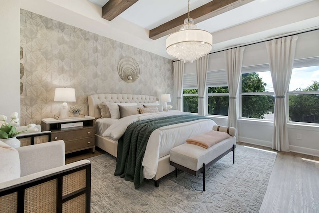 bedroom with light hardwood / wood-style floors, beamed ceiling, and an inviting chandelier