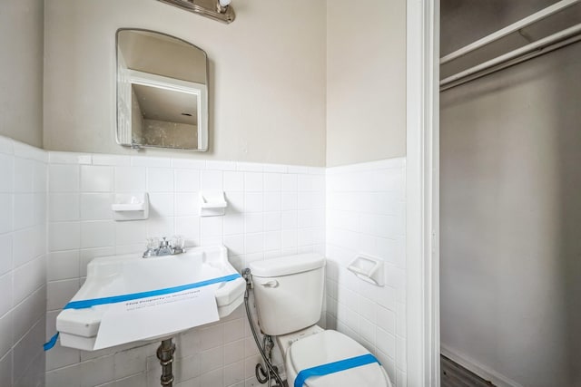 bathroom featuring toilet, sink, and tile walls