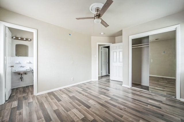 unfurnished bedroom with hardwood / wood-style floors, connected bathroom, sink, ceiling fan, and a closet