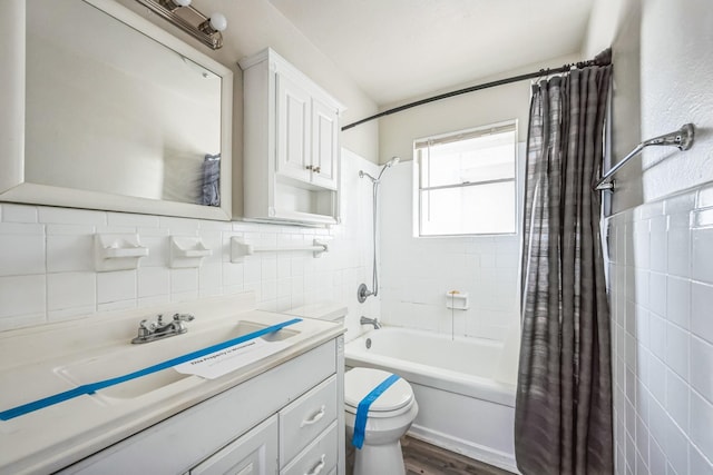 full bathroom with shower / bathtub combination with curtain, hardwood / wood-style flooring, tile walls, vanity, and toilet