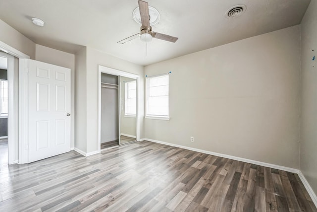 unfurnished bedroom with light wood-type flooring, ceiling fan, and a closet