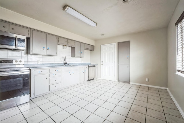 kitchen with light tile patterned floors, sink, appliances with stainless steel finishes, gray cabinetry, and decorative backsplash