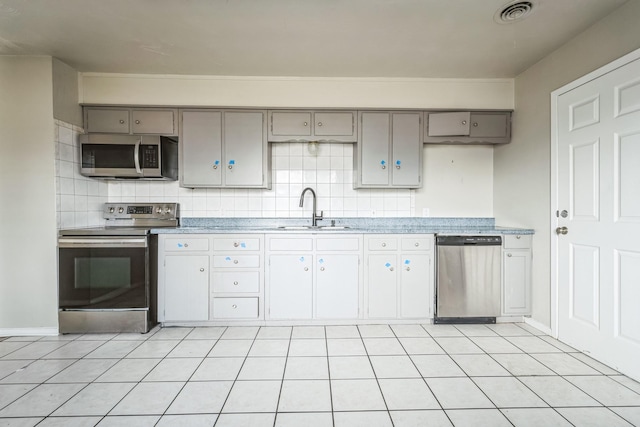 kitchen featuring sink, light tile patterned floors, gray cabinets, and stainless steel appliances