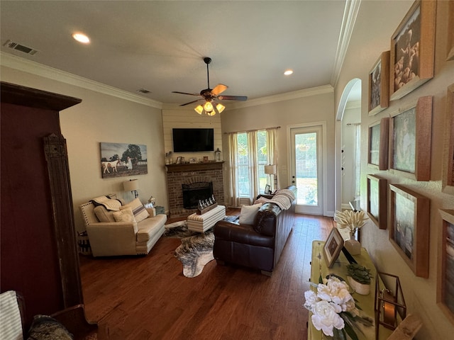 living room featuring ornamental molding, dark hardwood / wood-style floors, ceiling fan, and a brick fireplace