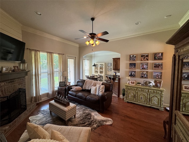 living room with ornamental molding, a brick fireplace, ceiling fan, and dark hardwood / wood-style flooring