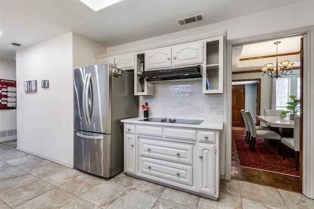 kitchen featuring white cabinetry, stainless steel refrigerator, an inviting chandelier, light hardwood / wood-style flooring, and black electric cooktop