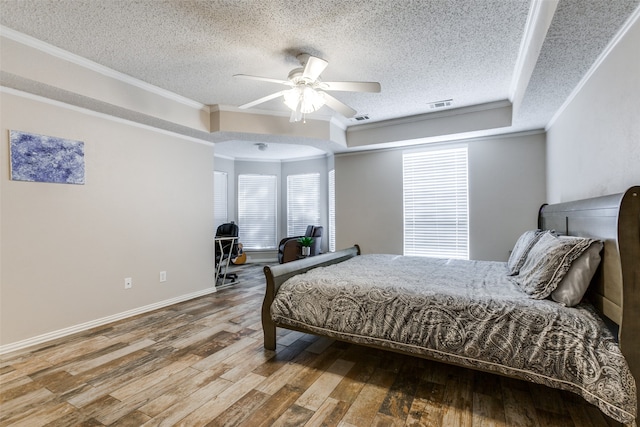 bedroom with a raised ceiling, a textured ceiling, crown molding, ceiling fan, and hardwood / wood-style floors