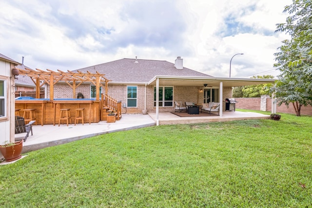 rear view of property featuring a patio, a pergola, and a lawn