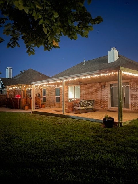 back house at night with a yard and a patio area