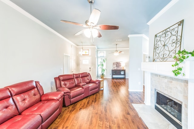 living room featuring ceiling fan, hardwood / wood-style flooring, a fireplace, and crown molding