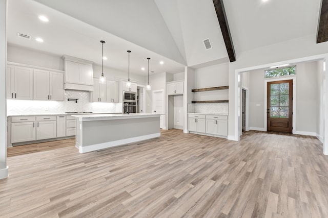 kitchen with white cabinets, tasteful backsplash, a kitchen island with sink, pendant lighting, and light wood-type flooring