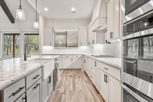 kitchen featuring sink, appliances with stainless steel finishes, backsplash, light hardwood / wood-style flooring, and white cabinets