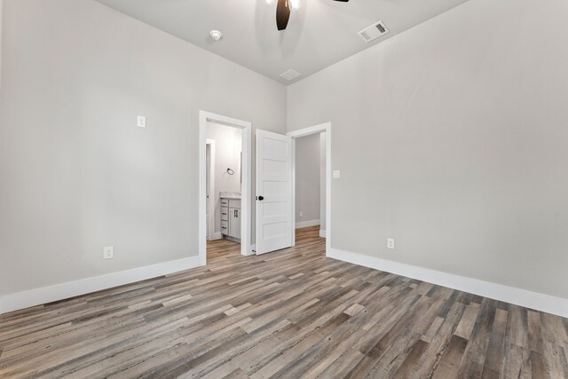 unfurnished bedroom featuring hardwood / wood-style floors, ceiling fan, and ensuite bathroom