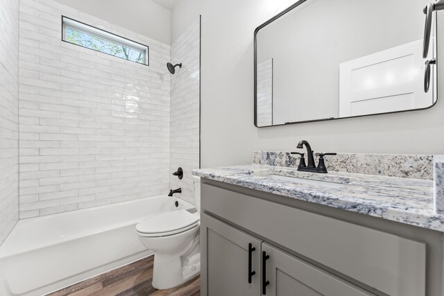 full bathroom with toilet, tiled shower / bath combo, vanity, and hardwood / wood-style flooring