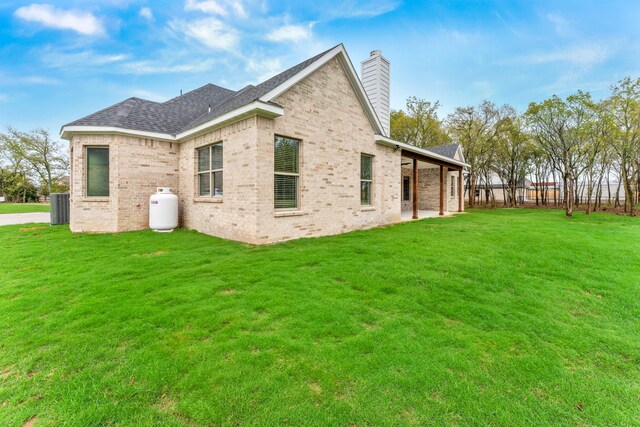 exterior space featuring central air condition unit and a lawn