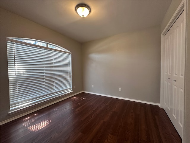 unfurnished bedroom featuring a closet and dark wood-type flooring