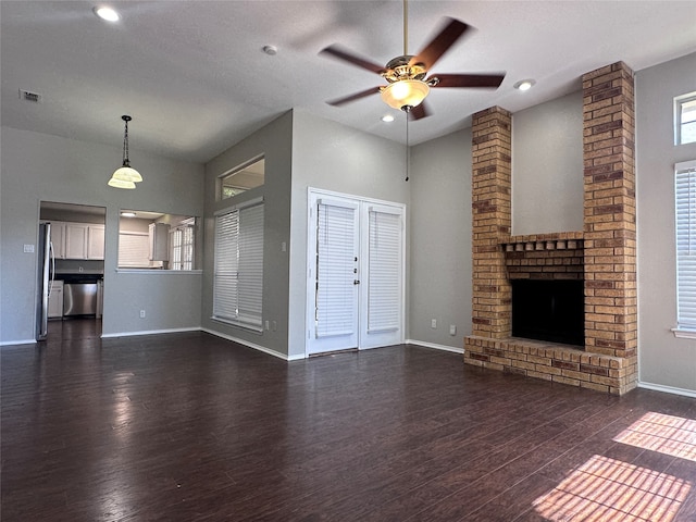 unfurnished living room featuring a fireplace, dark wood-type flooring, and ceiling fan